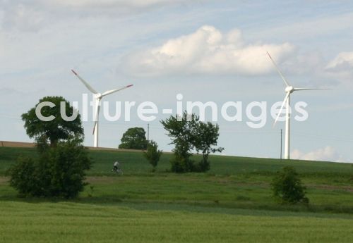 Radfahrer vor Windrädern in Feldern